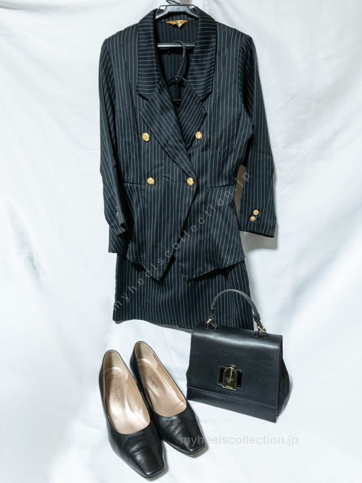 （非着用）ピンストライプスーツと黒パンプスの配置写真 白背景
